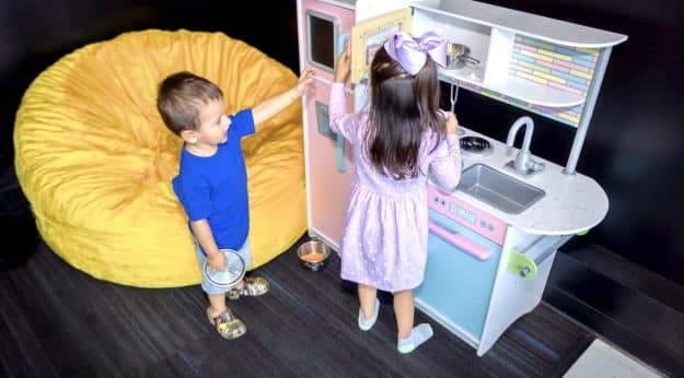 Two children playing with toy kitchen